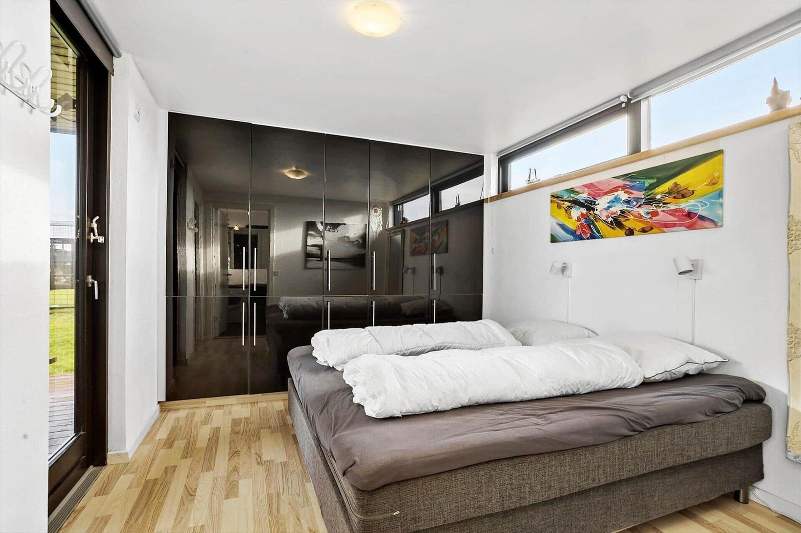 Bedroom with bed, wardrobe, and windows.