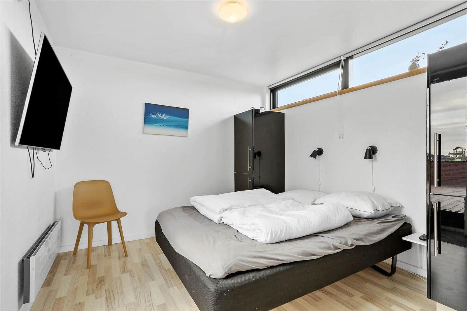 Bedroom with bed, wardrobe, and TV mounted on the wall.