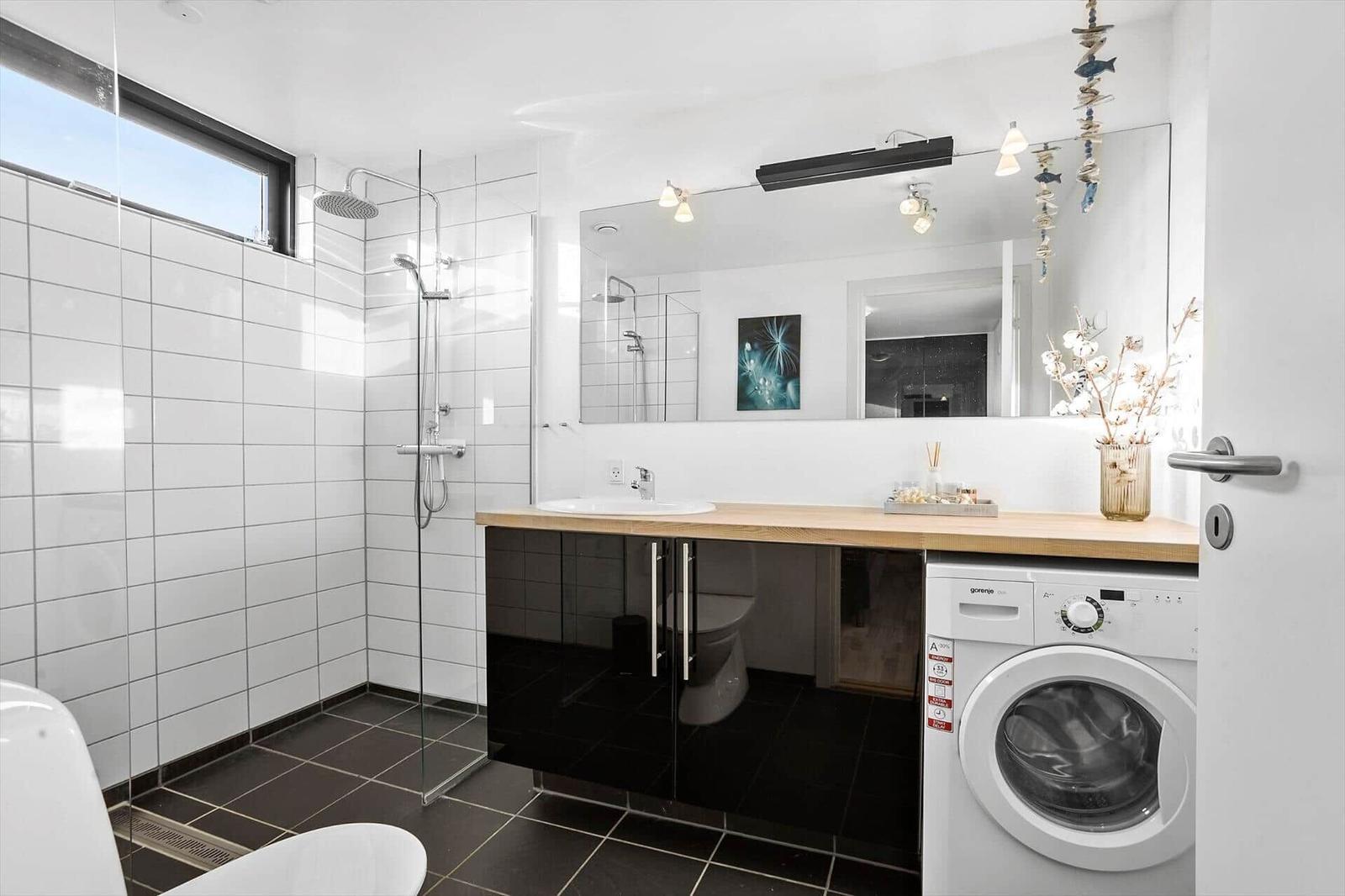 Bathroom with shower, washing machine, and mirror cabinet