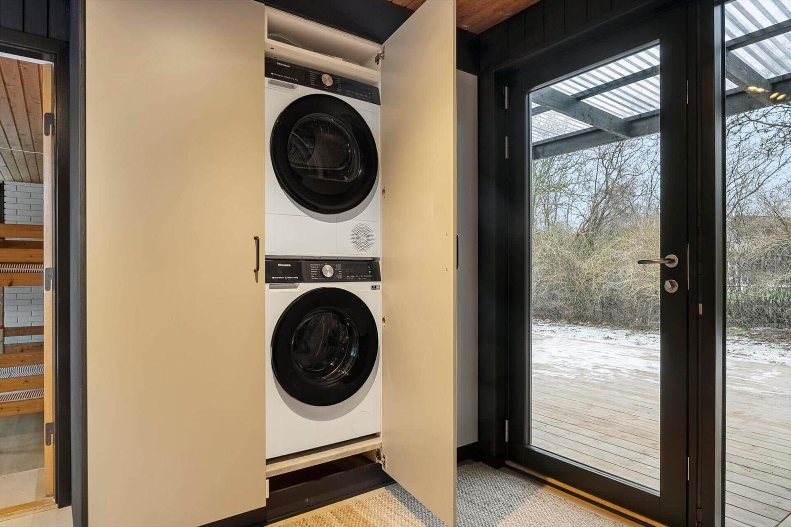 Tumble dryer and washing machine in built-in cabinet. Glass door opens to terrace.