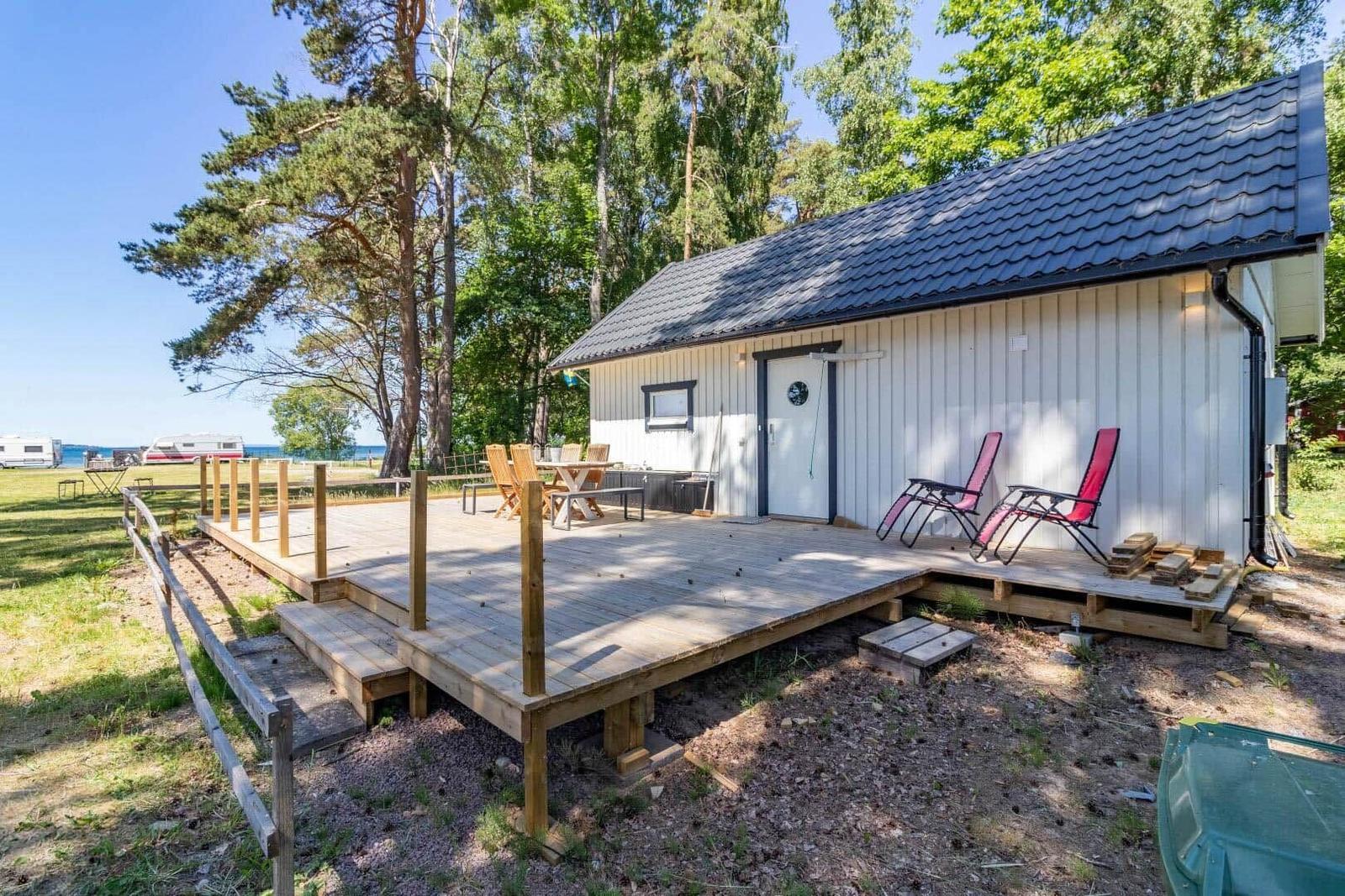 Wohnhaus mit Holzterrasse, Sonnenliegen und Blick auf den See.