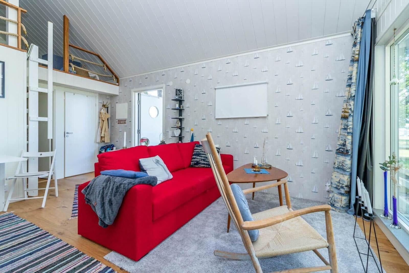 Ein Wohnzimmer mit rotem Sofa, Holzstuhl und Segelwandtapete.