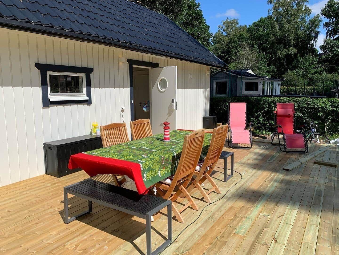 Terrasse mit Tisch, Stühlen und Liegestühlen vor einem Haus.