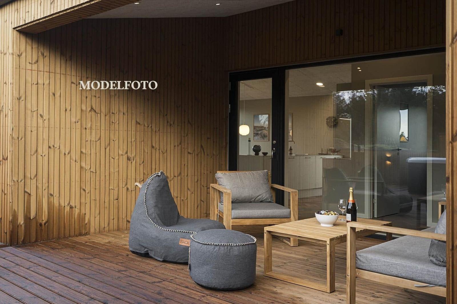 Terrasse mit Holzwand, Sitzgelegenheiten und Blick ins Haus.