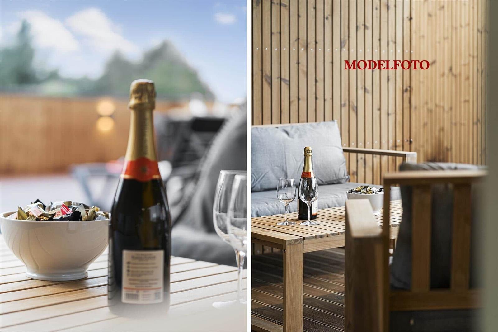 Auf der Terrasse steht ein Tisch mit einer Champagnerflasche und Gläsern.