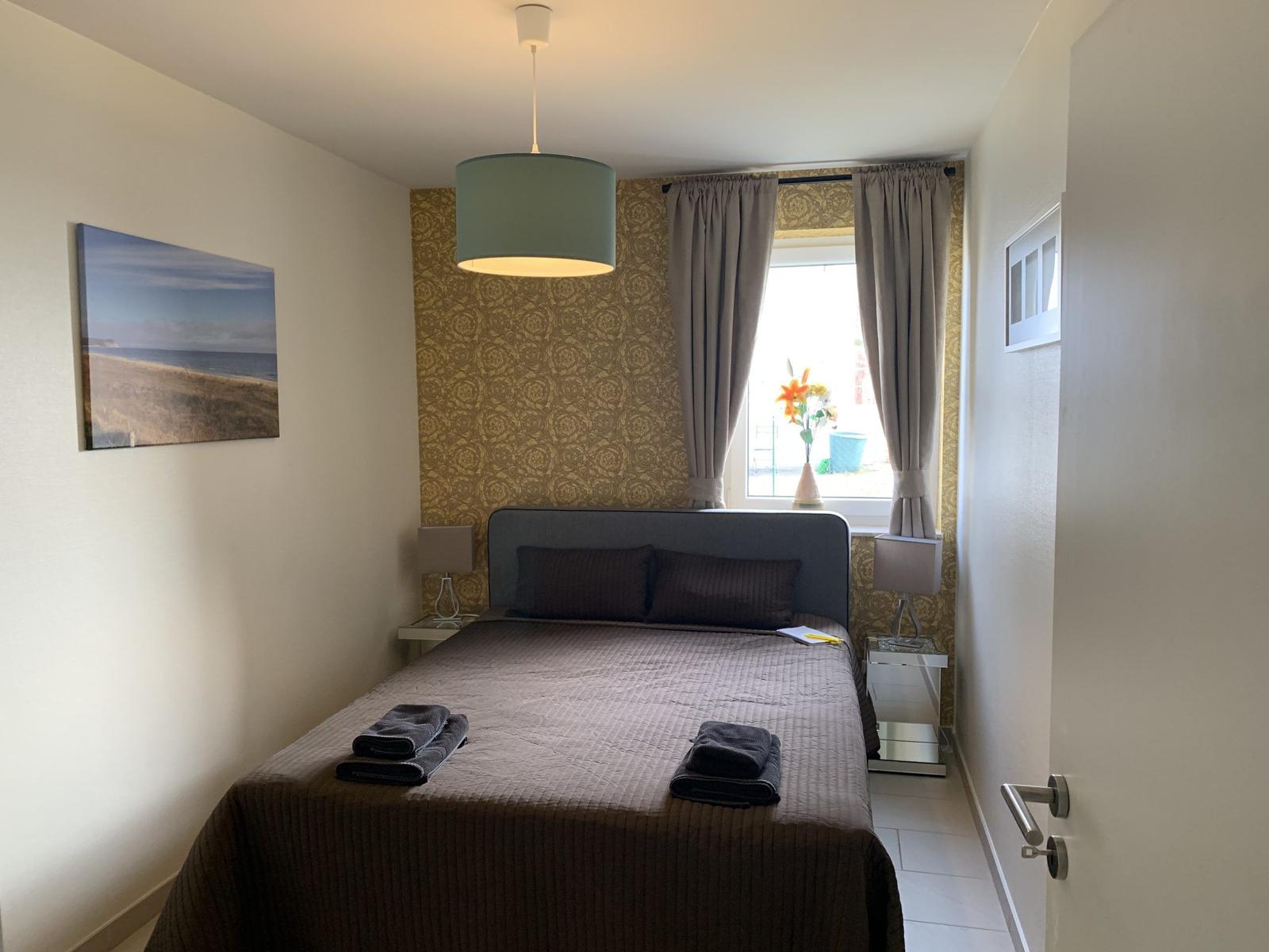 Schlafzimmer mit Bett, Fenster und Wandbild.