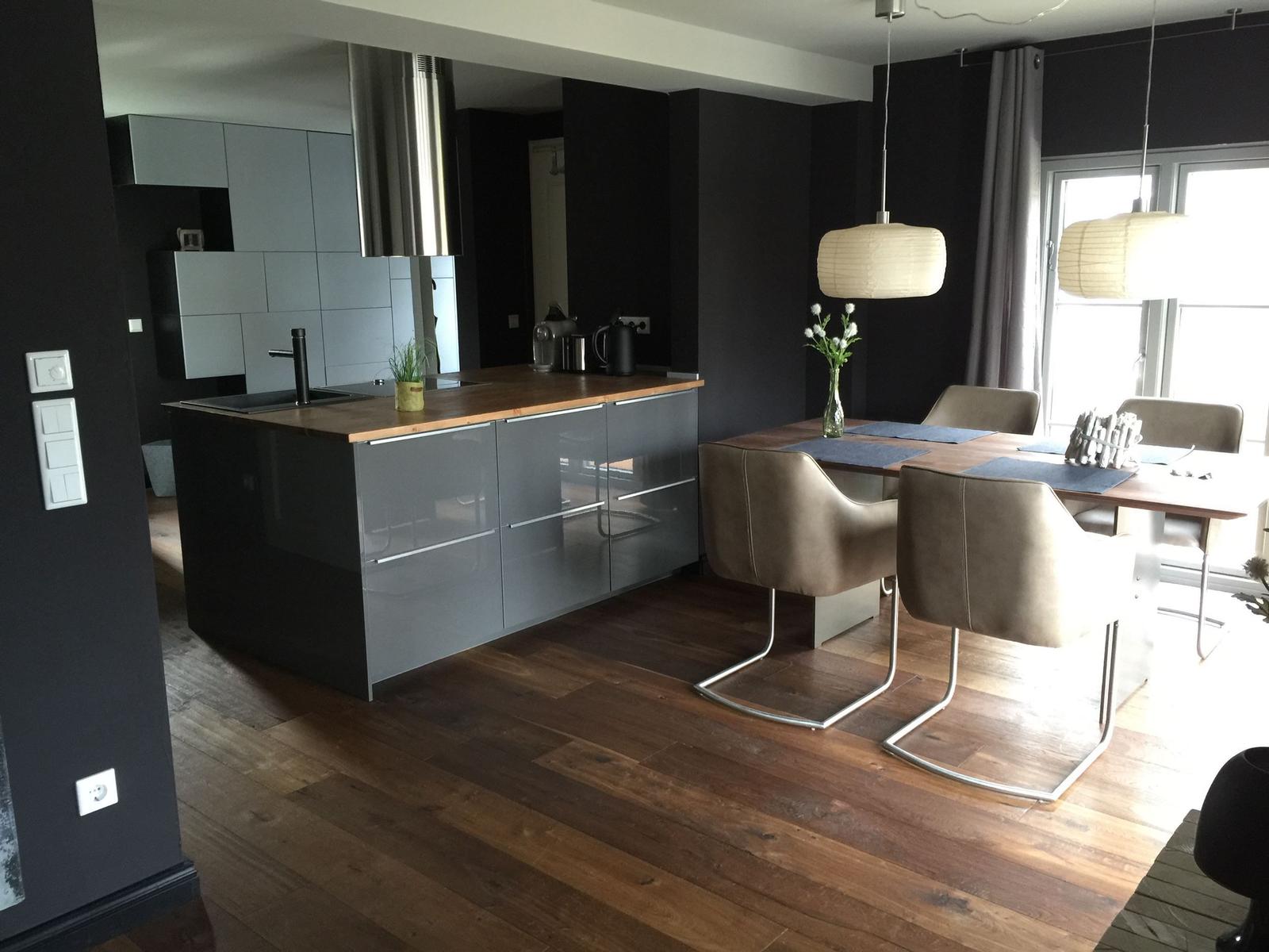 Küche mit Essbereich, Holzboden und modernen Lampen.