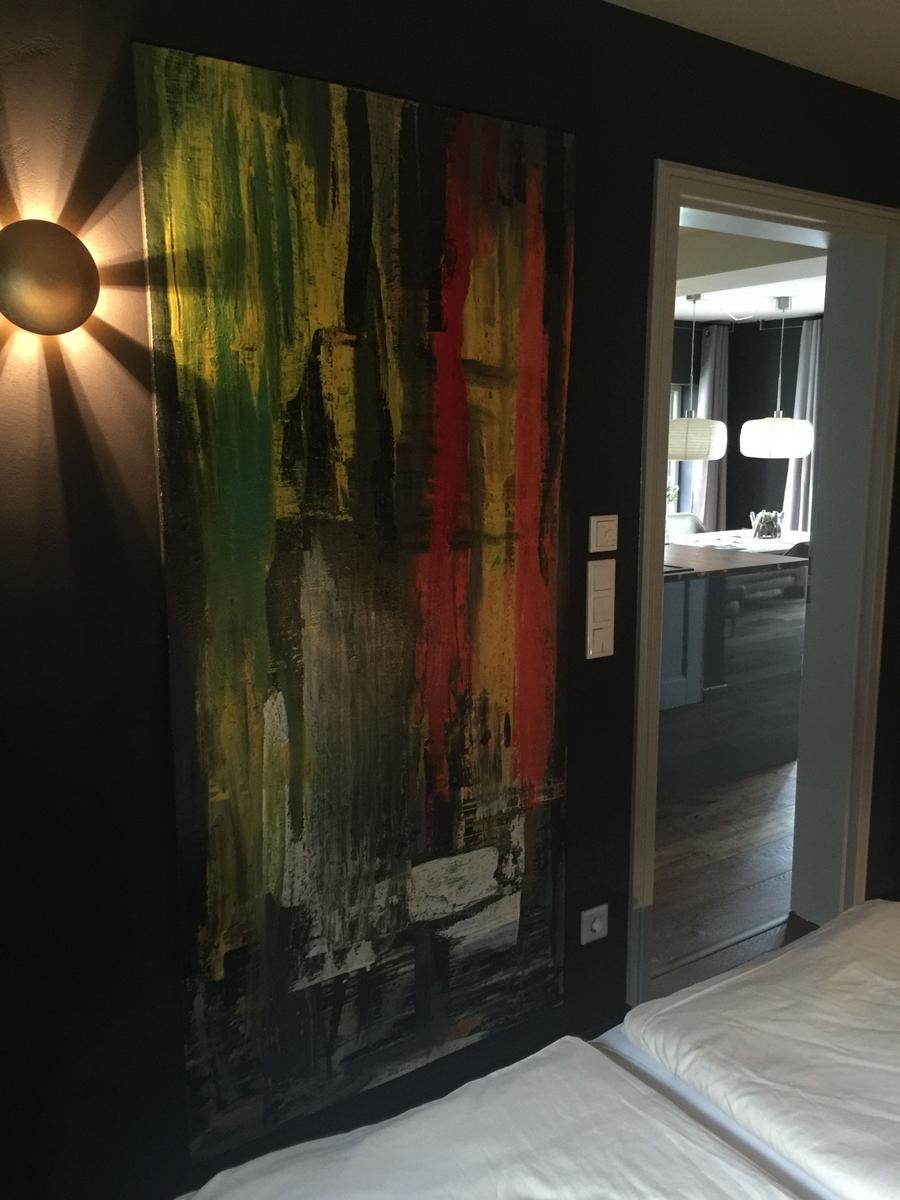 Schlafzimmer mit großer Wandmalerei und Sicht in die Küche.