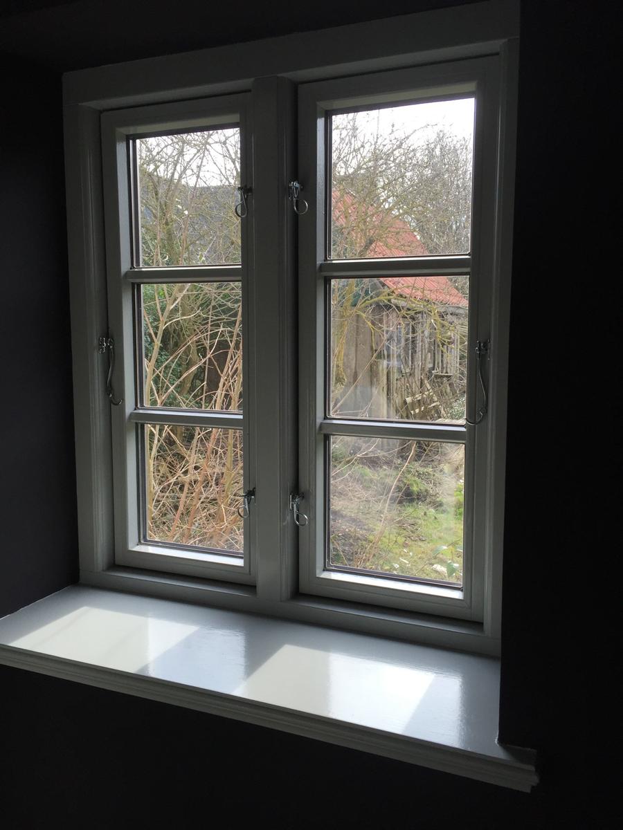 Fenster mit Blick auf einen Garten und eine Hütte mit rotem Dach.