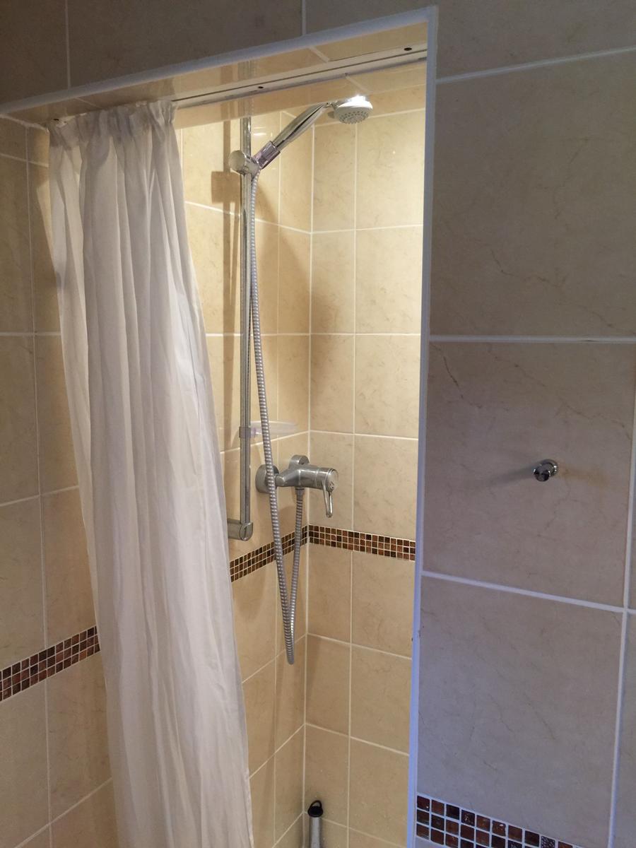 Dusche mit Duschbrause und weißen Vorhängen