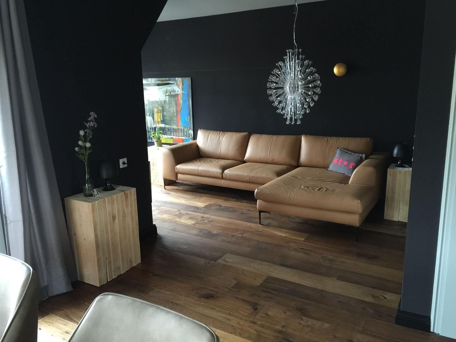 Ein Wohnzimmer mit braunem Sofa, dunklen Wänden und Holzboden.