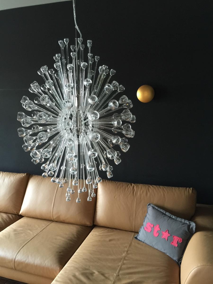 Ein Sofa mit Kissen und einer Glasleuchte an der Wand.