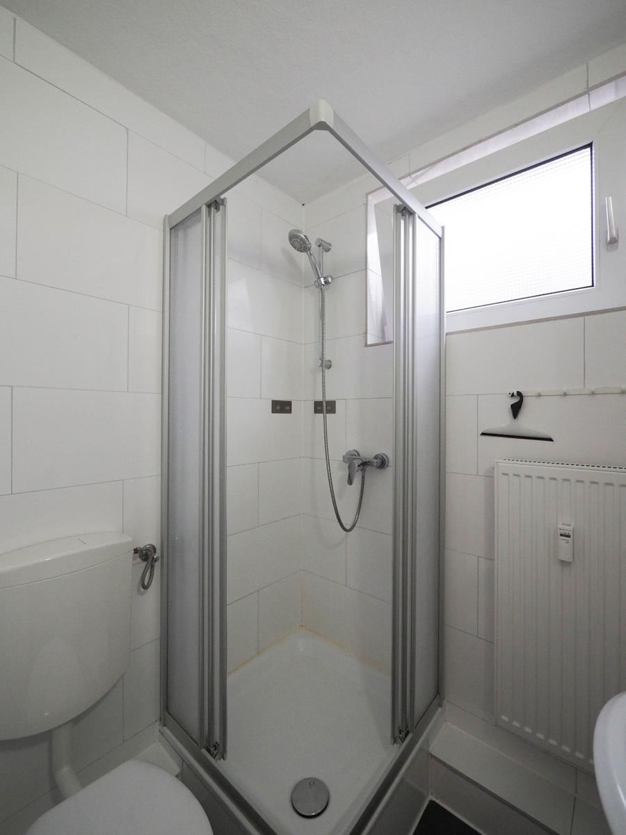 Duschkabine mit Duschbrause, Toilette und Fenster