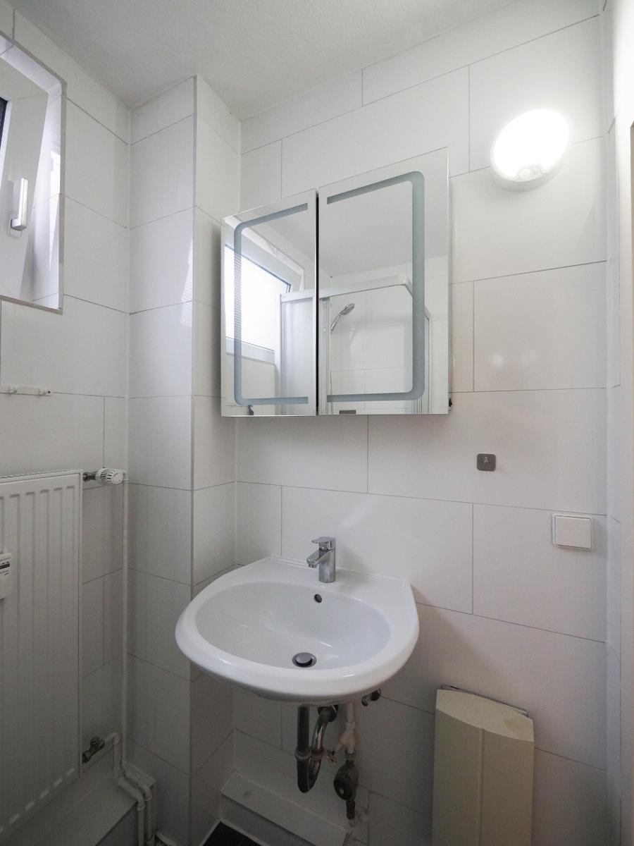 Badezimmer mit Waschbecken, Spiegelschrank und Fenster.