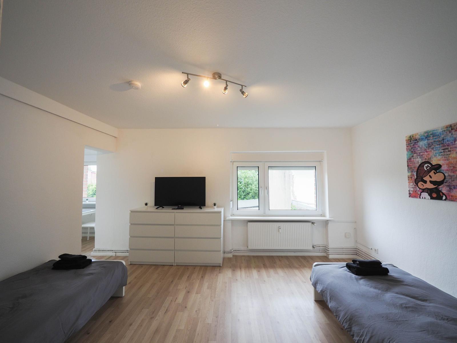 Zwei Einzelbetten, Fernseher und Fenster mit Blick nach außen.