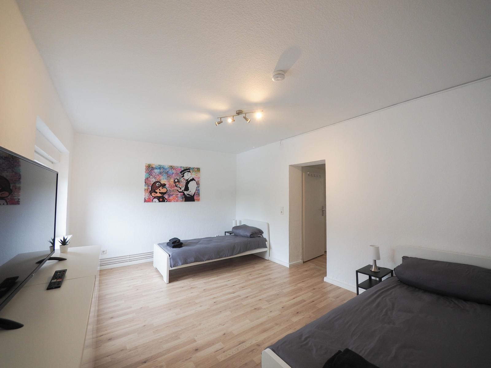 Zwei Betten, Fernseher und Wandbild im Schlafzimmer.