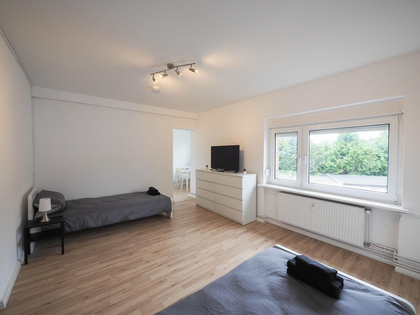 Zwei Betten, Fernseher und Fenster mit Blick auf Grün.