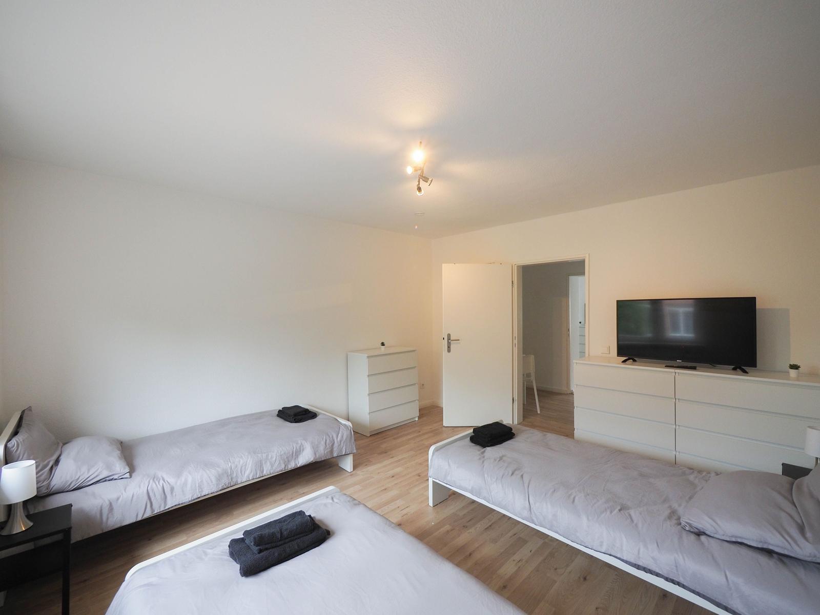 Drei Betten, Fernseher und Schränke im Schlafzimmer