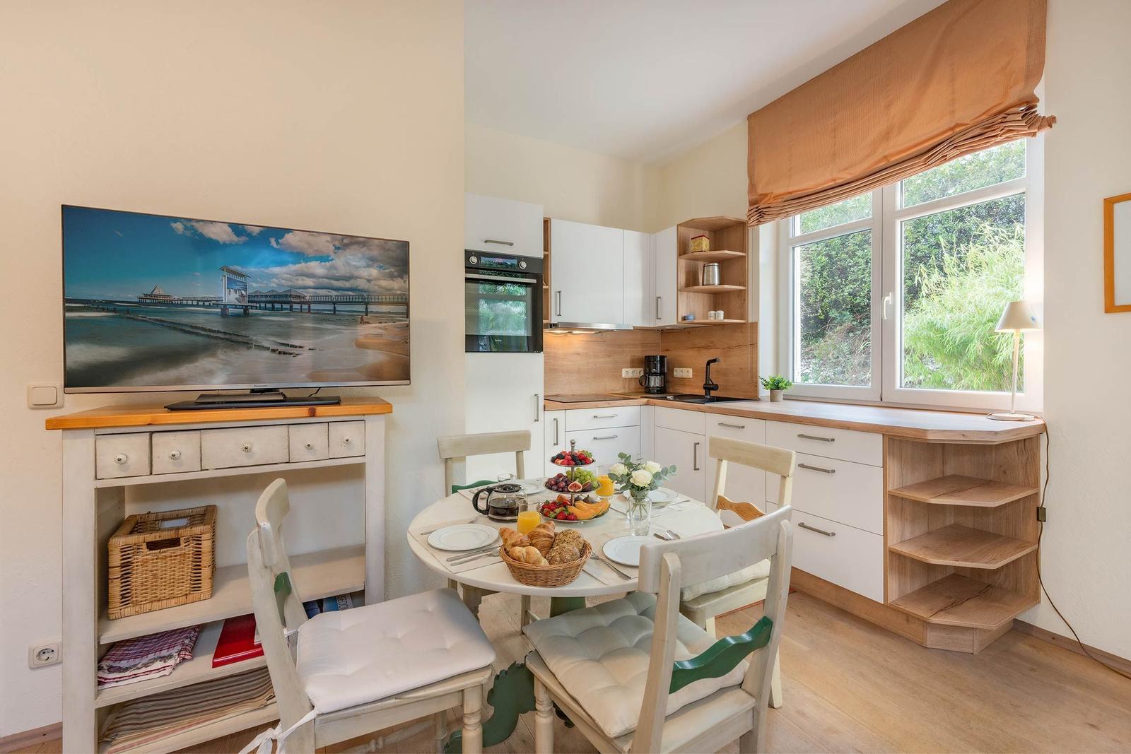 Küche mit Esstisch, Fernseher und Fenster mit Blick auf Grün
