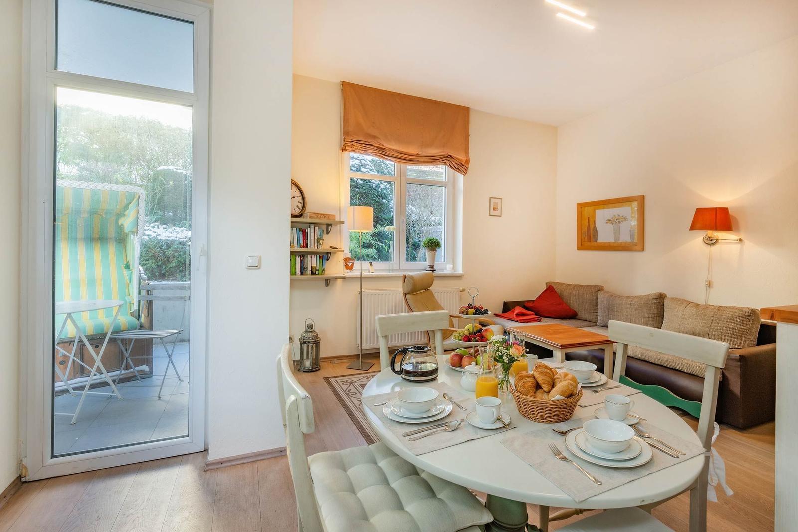 Esszimmer mit Tisch, Stühlen und Frühstück. Wohnbereich mit Sofa und Fenster.