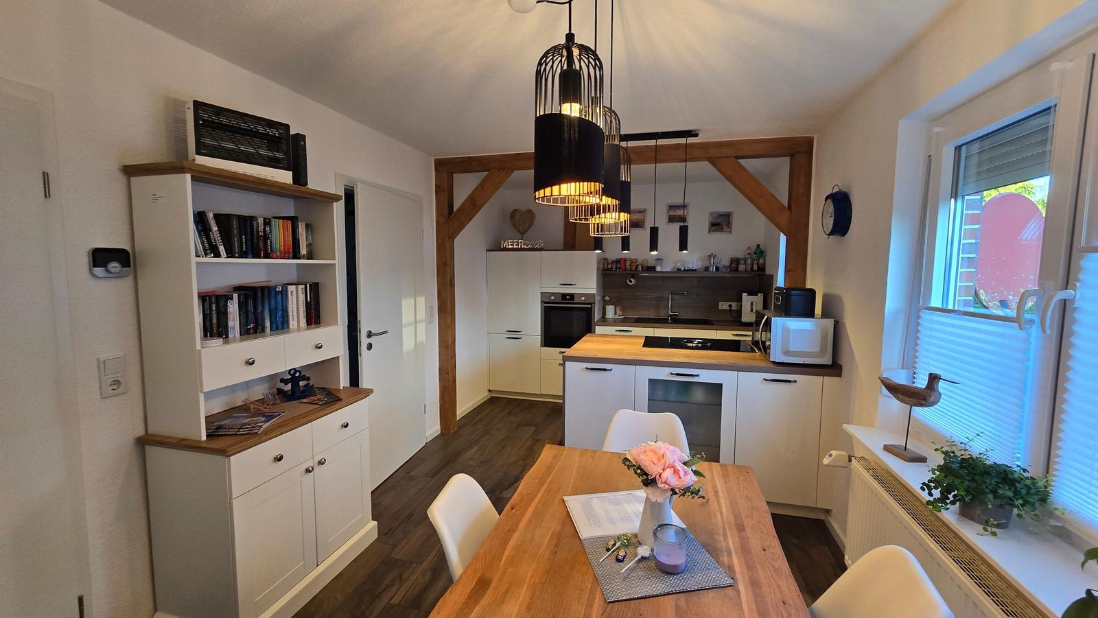 Essbereich mit Holztisch, Küche mit weißen Schränken und Holzoberflächen.