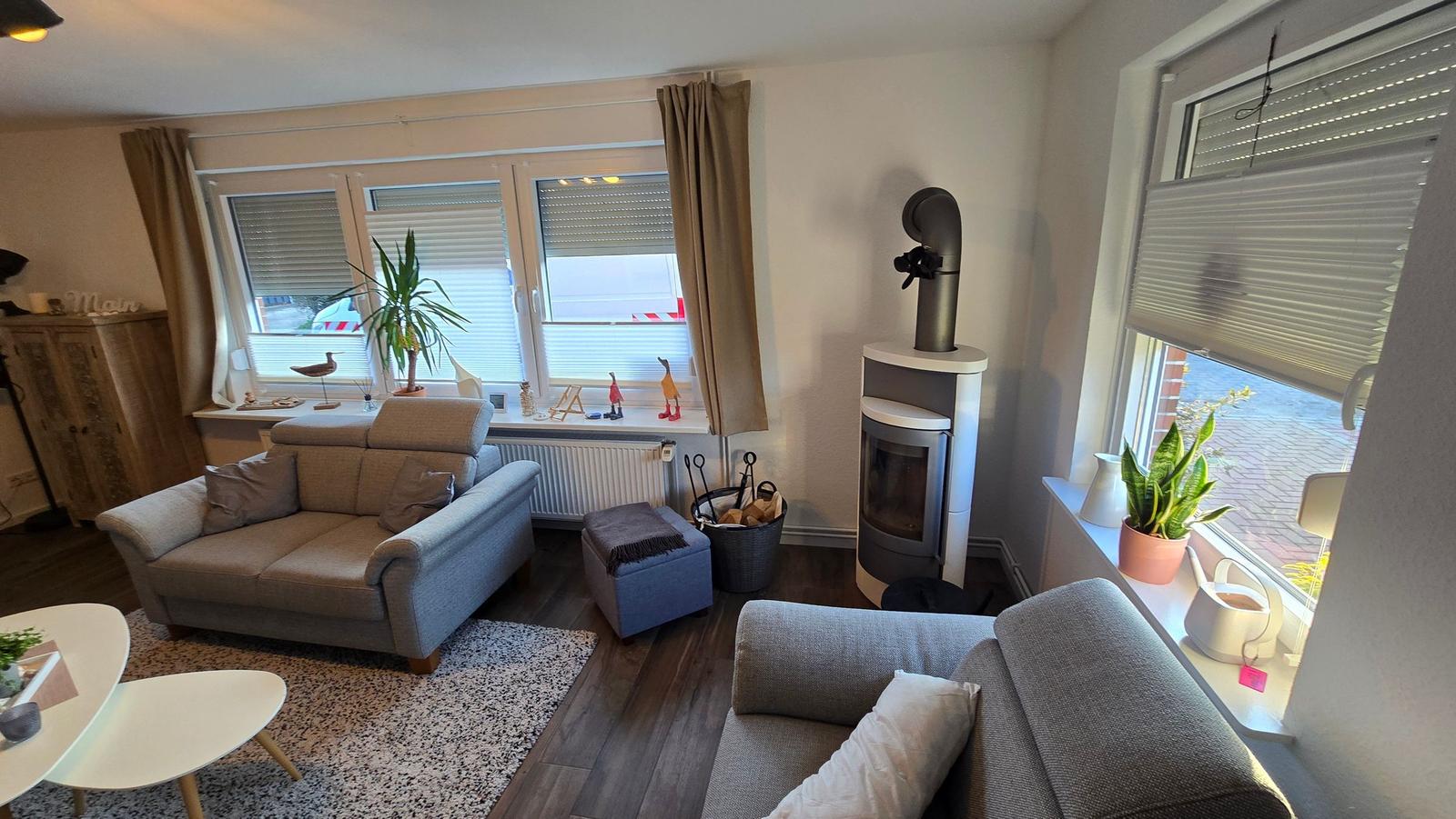 Wohnzimmer mit Sofa, Kamin und Fenstern.