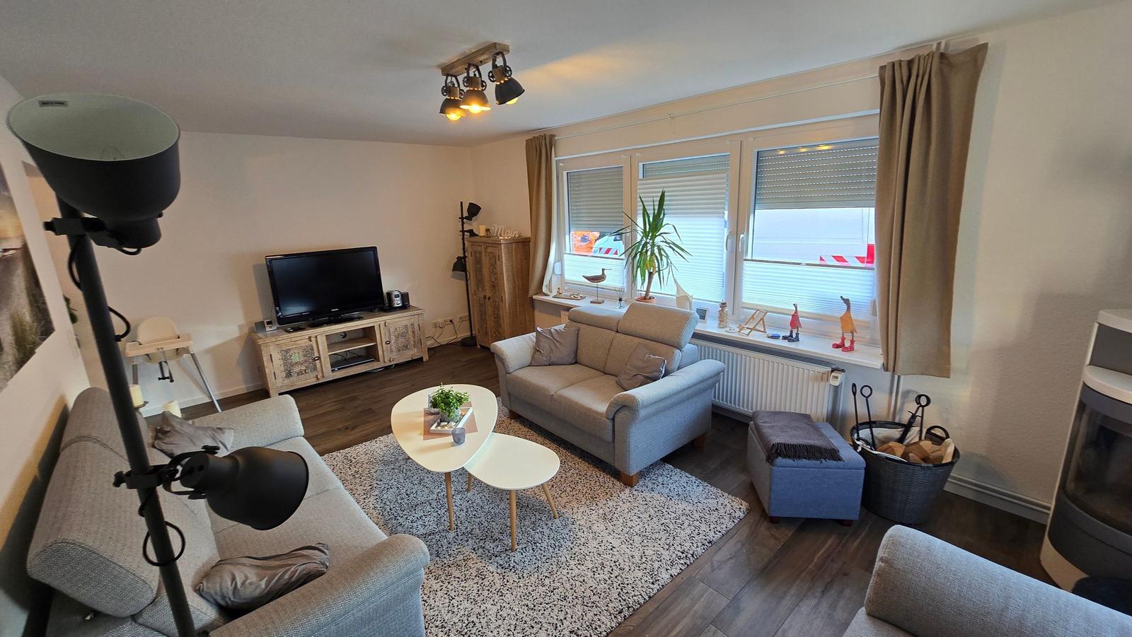 Wohnzimmer mit Sofa, Fernseher und Fenster