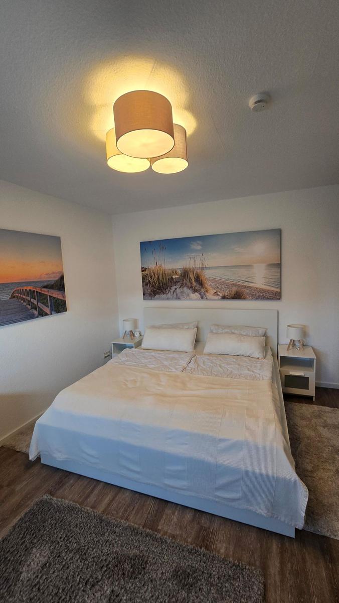 Schlafzimmer mit Doppelbett, zwei Nachttischen und Wandbildern