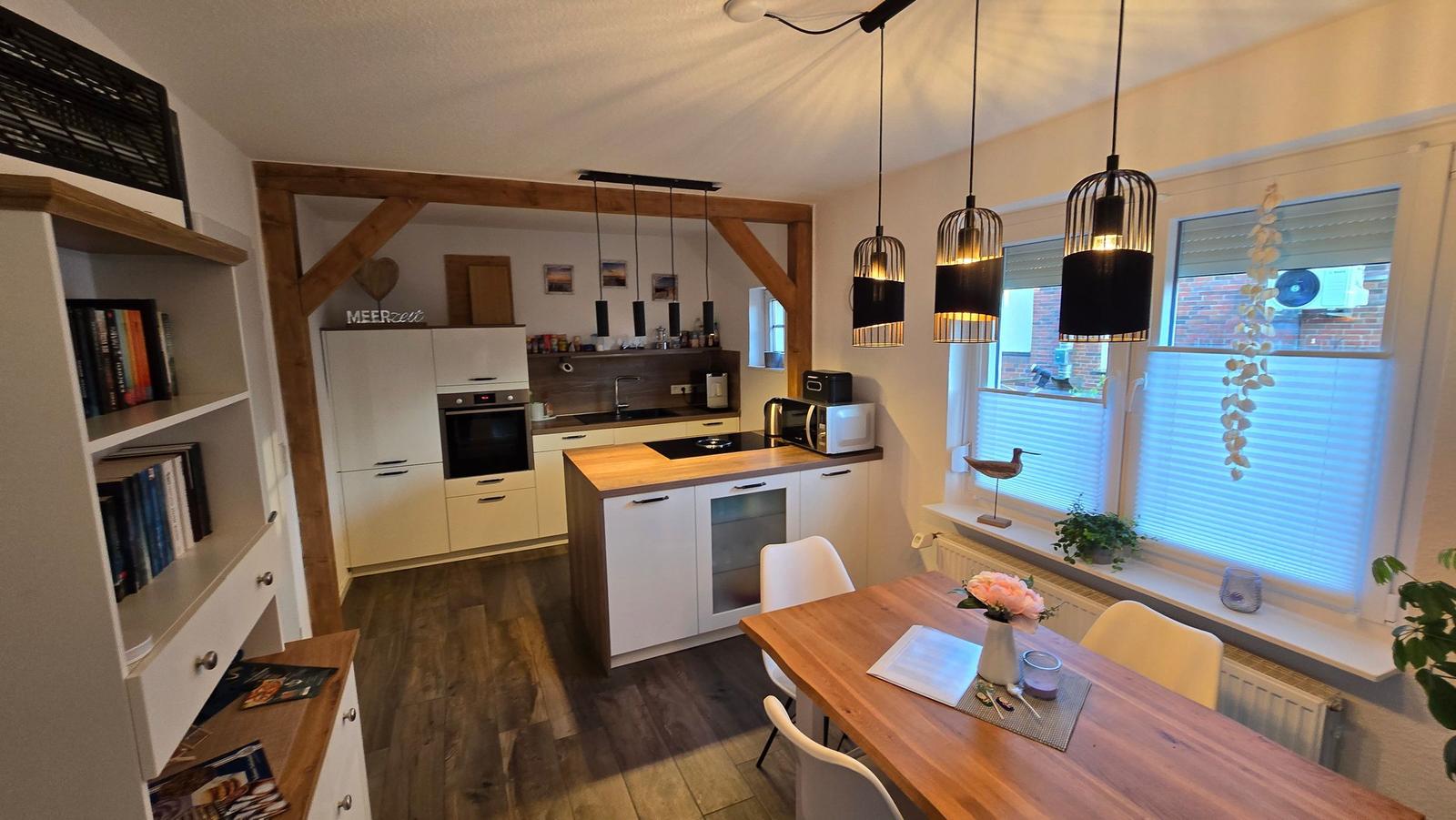 Küche mit Essbereich, Holzboden und modernen Hängelampen.