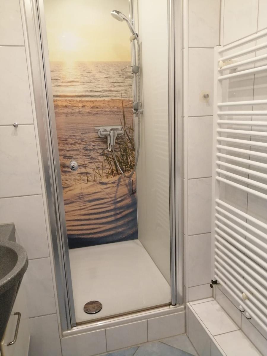 Duschkabine mit Strandmotivwand, Handbrause und Heizkörper