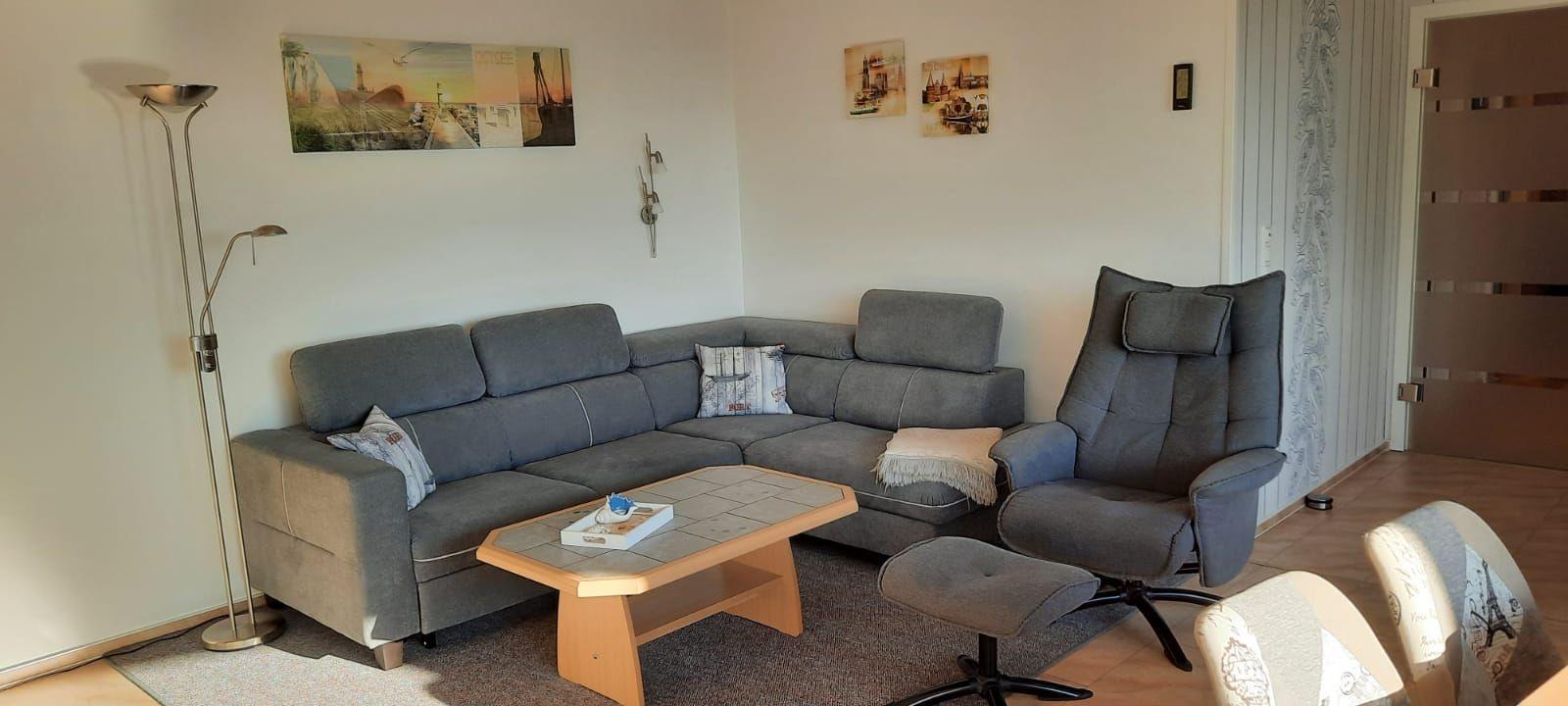Wohnzimmer mit grauem Sofa, Sessel und Holztisch