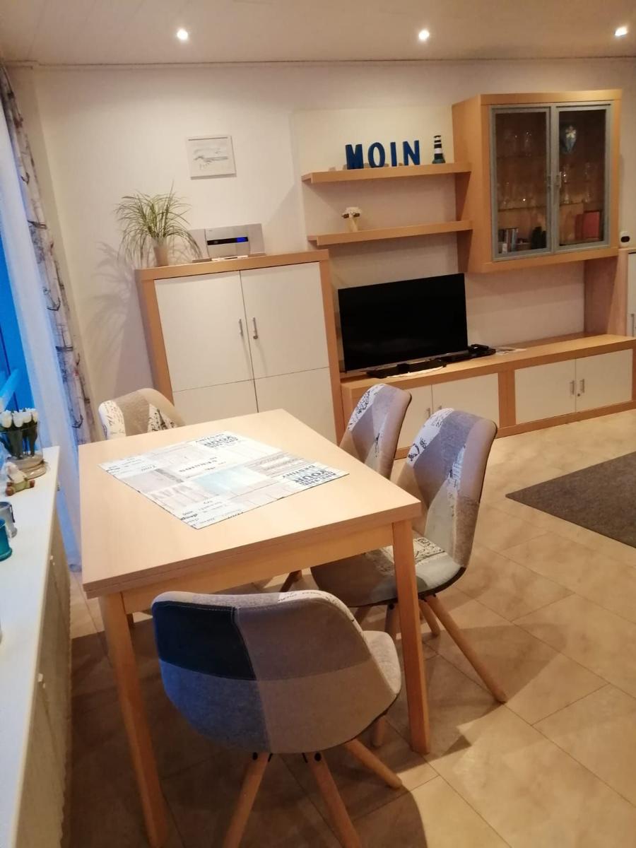 Essbereich mit Tisch, Stühlen und Fernseher im Wohnbereich.