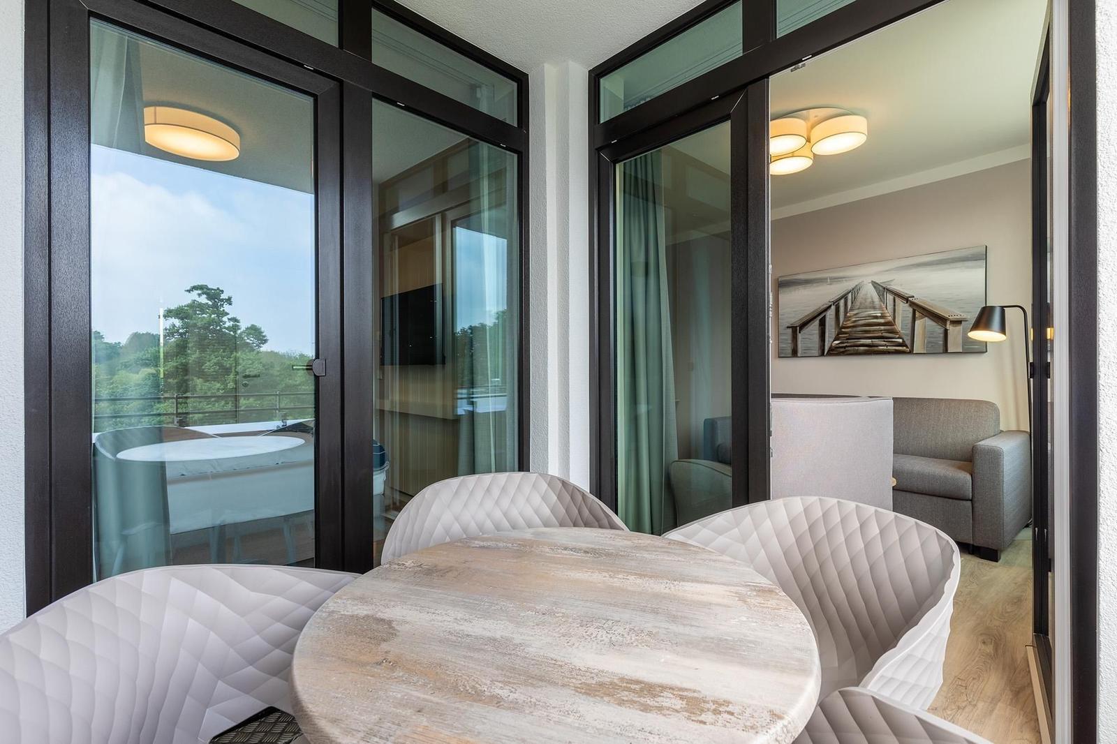 Essbereich mit Tisch und Stühlen, Blick auf Balkon und Wohnzimmer.