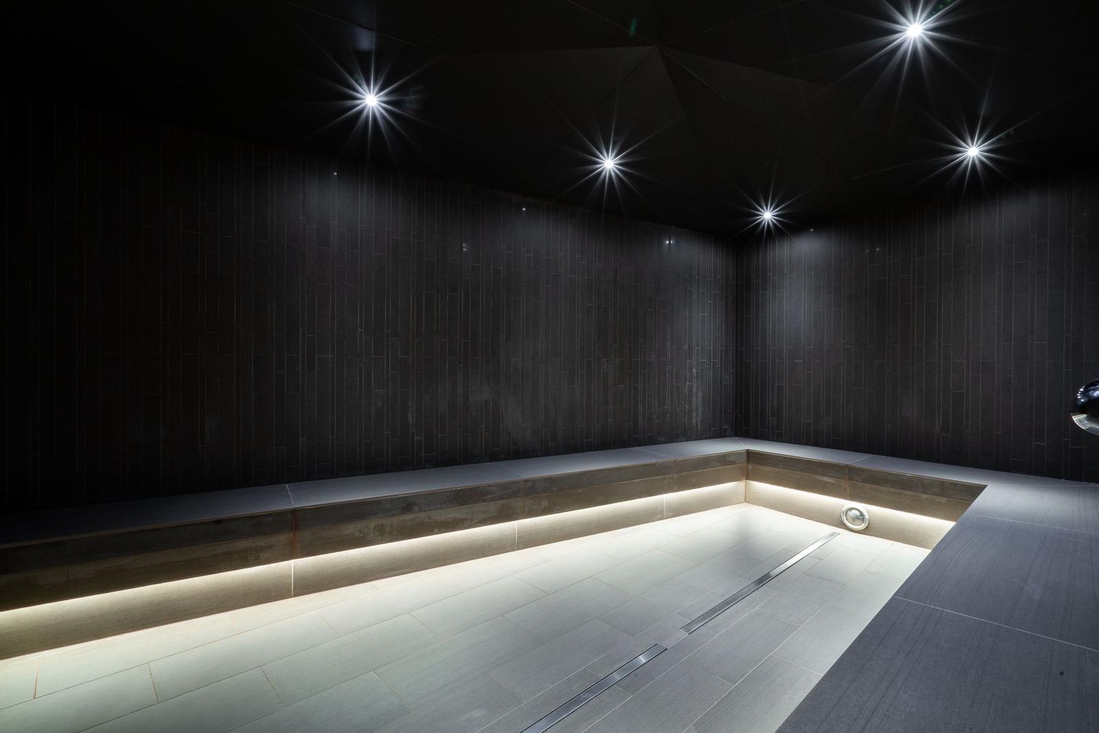 Dusche mit dunklen Wänden und eingebauter Beleuchtung