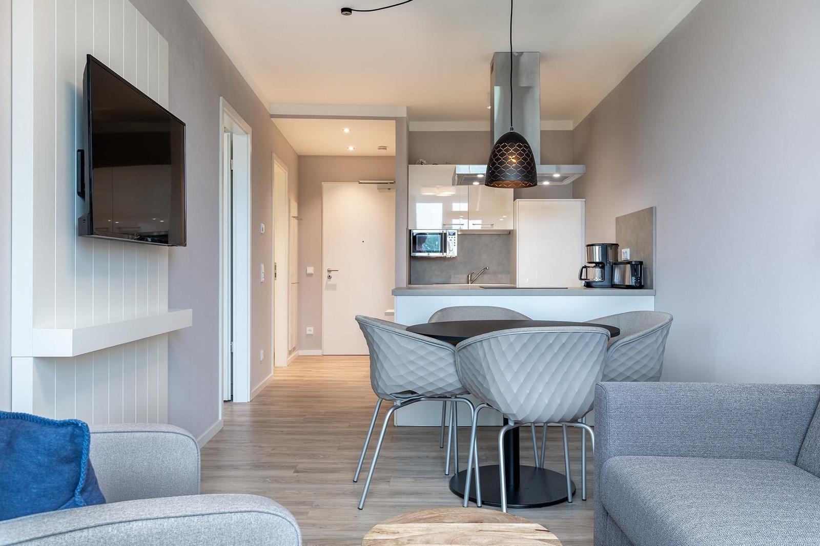 Wohn- und Essbereich mit Küchenzeile und TV.