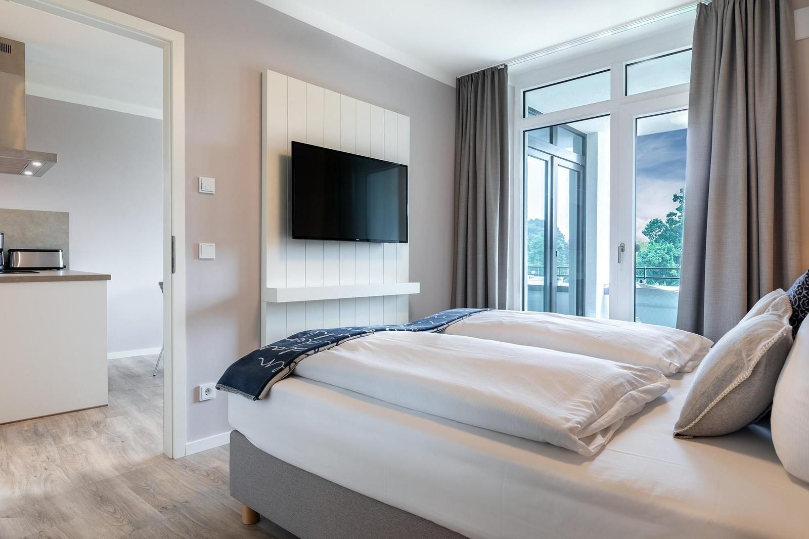 Schlafzimmer mit Doppelbett, TV und Balkonzugang.