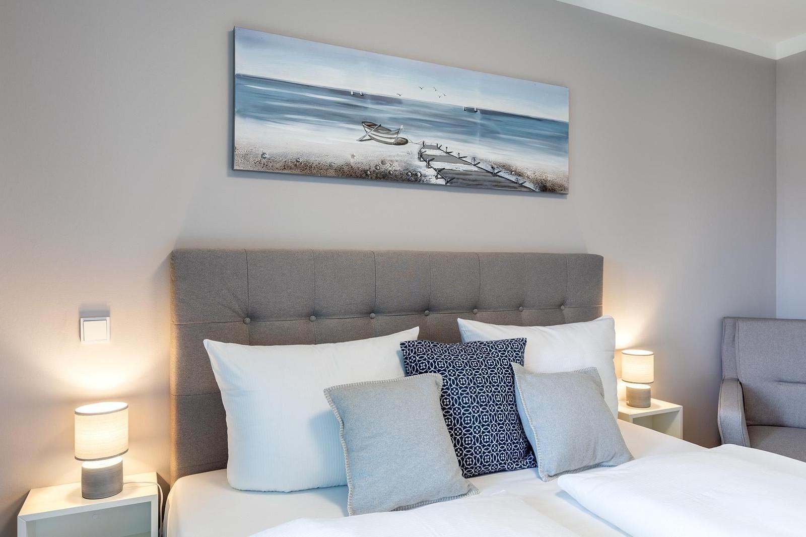 Schlafzimmer mit Bett, Kissen und Wandbild an der Wand.