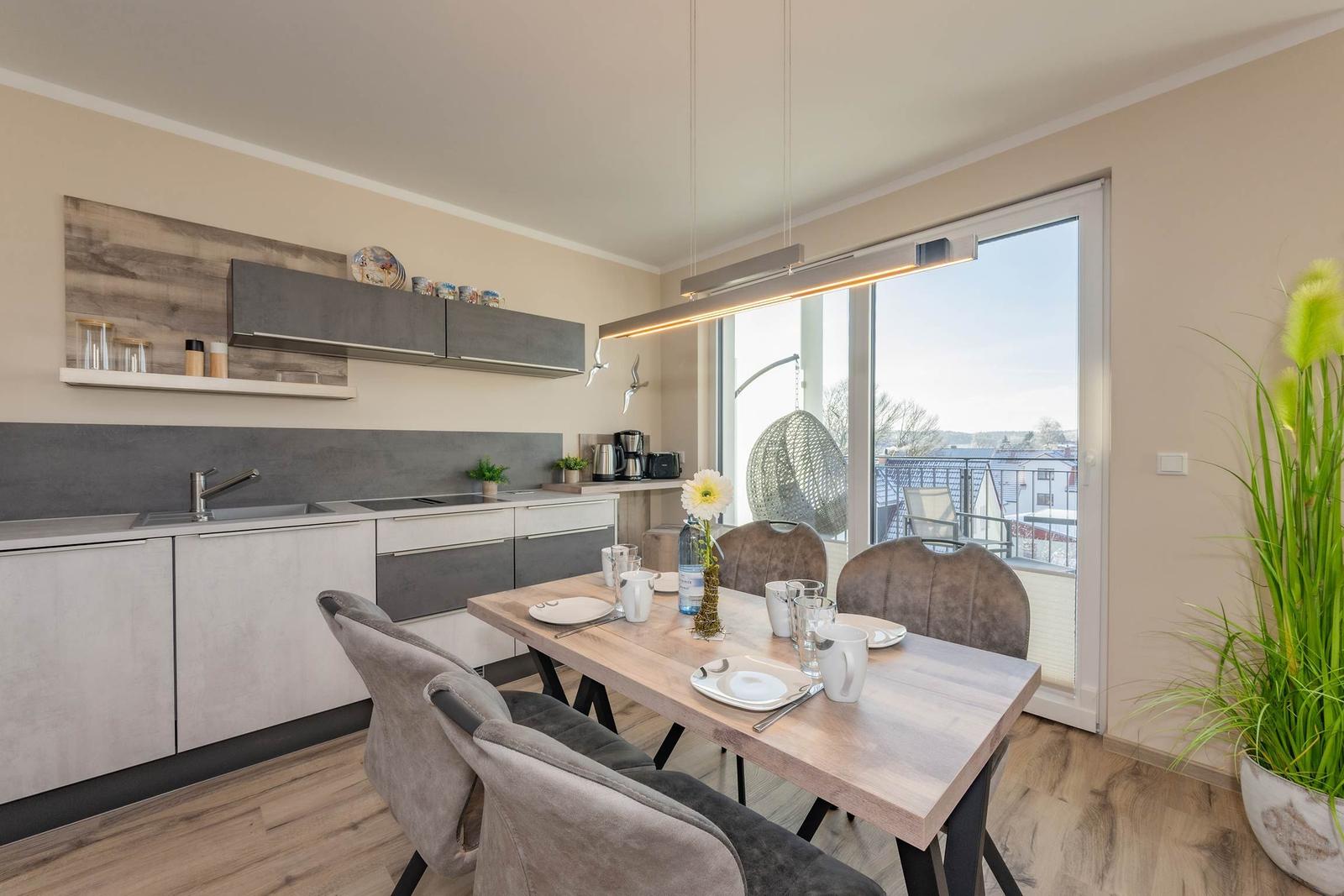 Küche mit Esstisch und Blick auf Balkon mit Hängesessel.