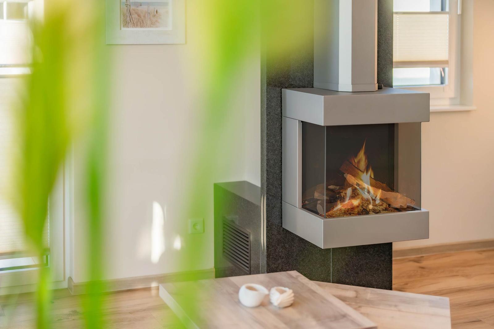 Moderne Wandhalterung mit brennendem Kamin, Holzfußboden und Fenster im Hintergrund.