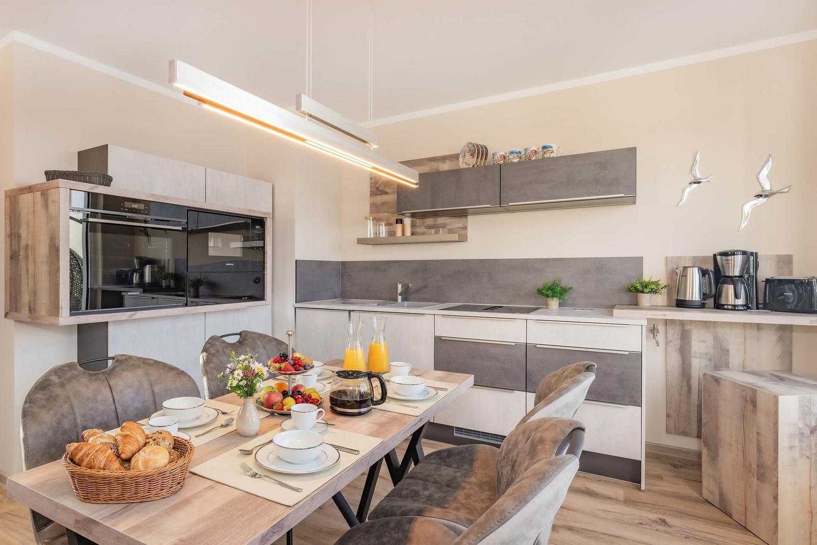 Küche mit Esstisch, modernen Schränken und Küchengeräten.