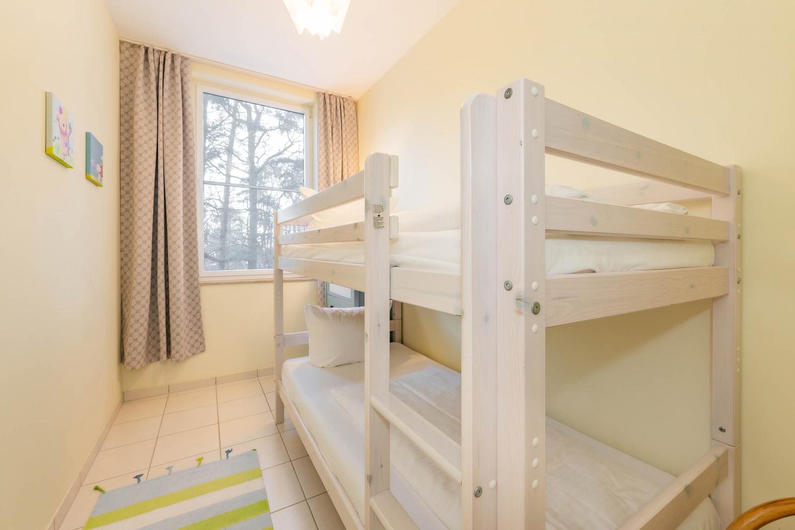 Zimmer mit Doppelstockbett, Fenster und Teppichboden.