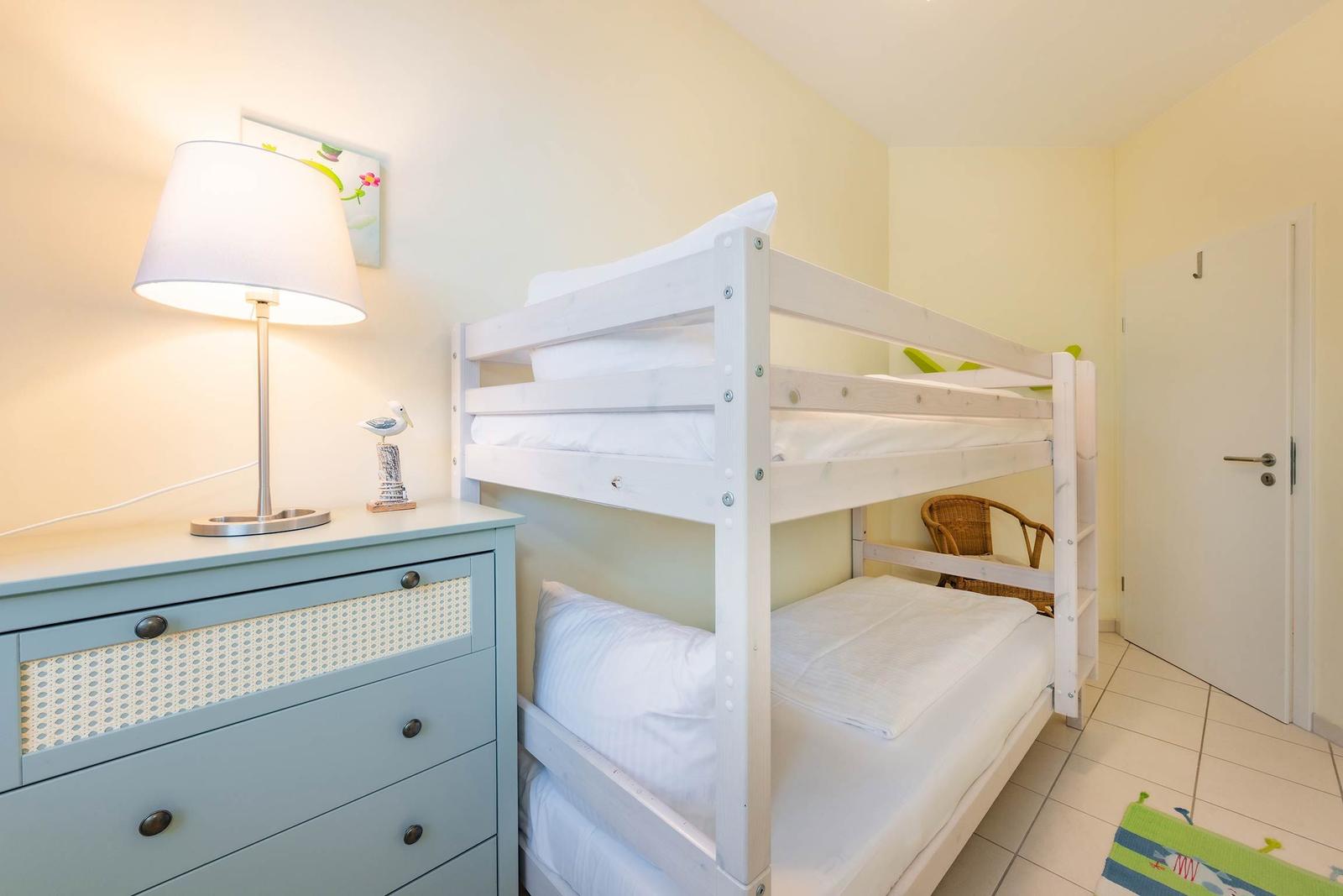 Zimmer mit Doppelstockbett, Schrank und Lampe.