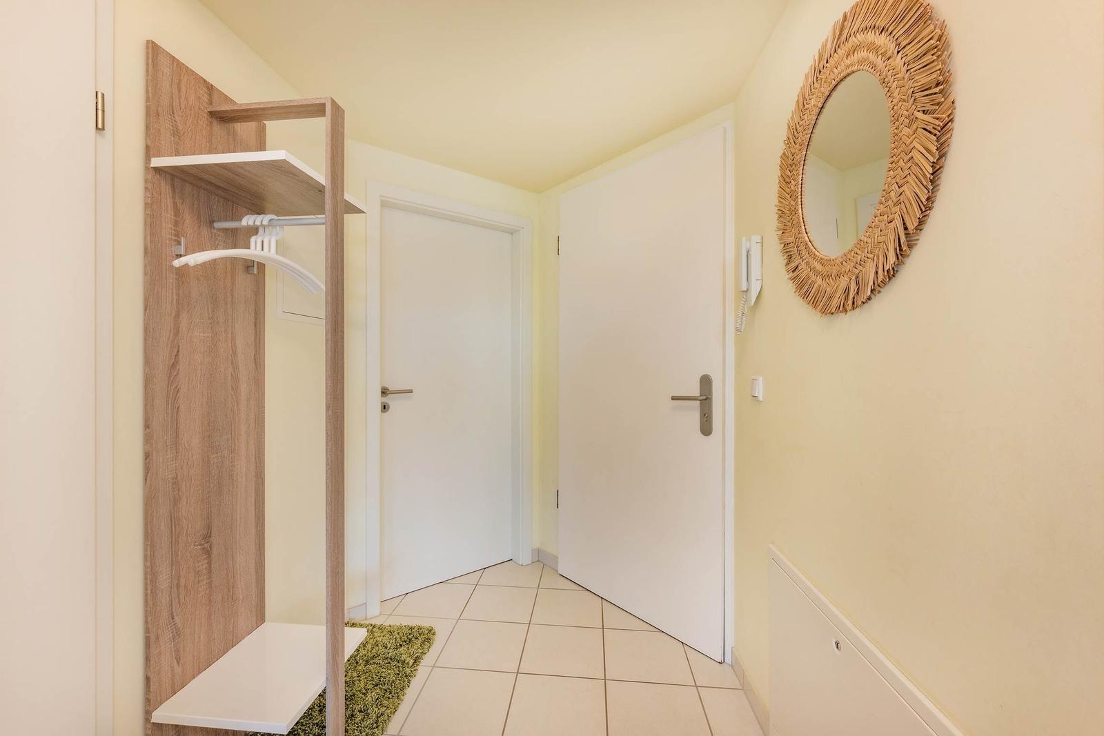 Flur mit Kleiderschrank, Spiegel und zwei Türen.