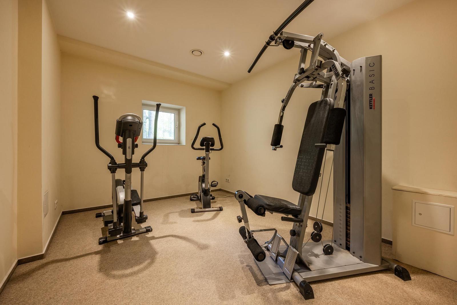 Fitnessraum mit Laufband, Fahrrad und Kraftstation.