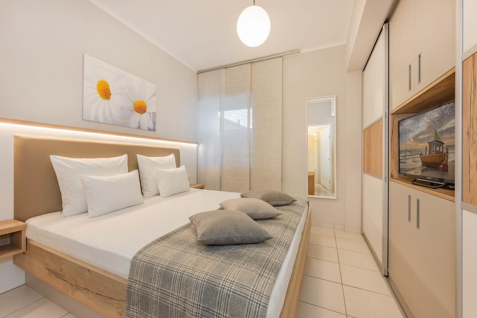 Schlafzimmer mit Bett, TV und Kleiderschrank