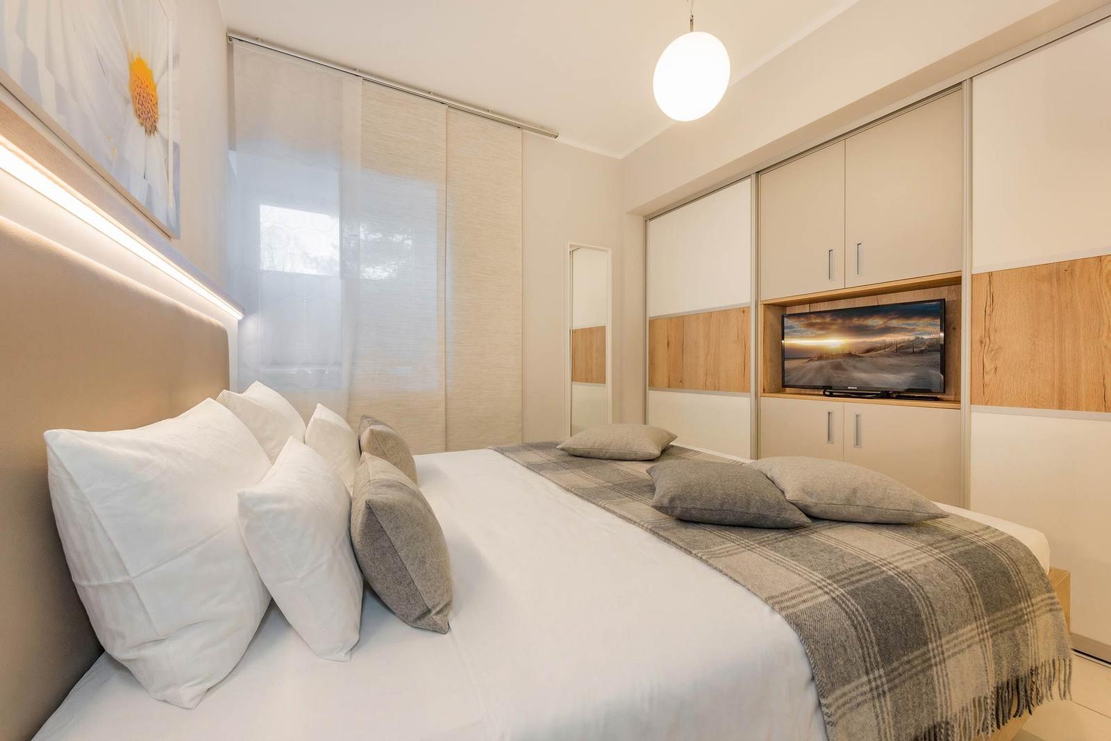 Schlafzimmer mit Bett, Kleiderschrank und eingebautem Fernseher.