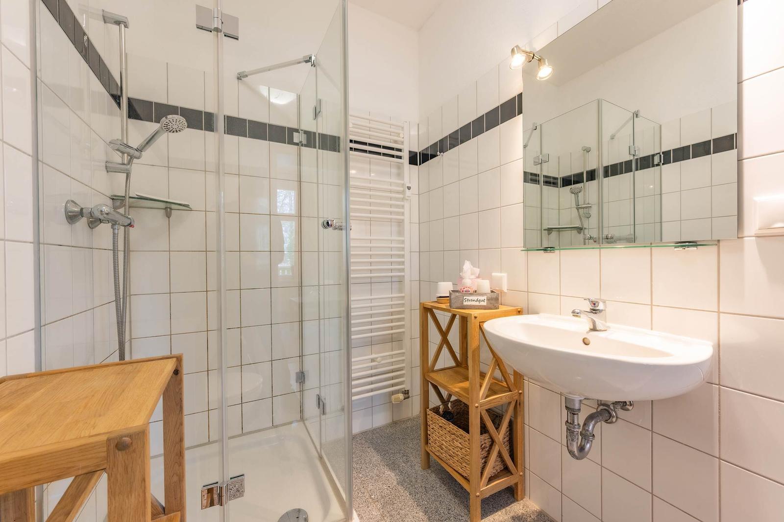 Badezimmer mit Dusche, Waschbecken und Spiegel