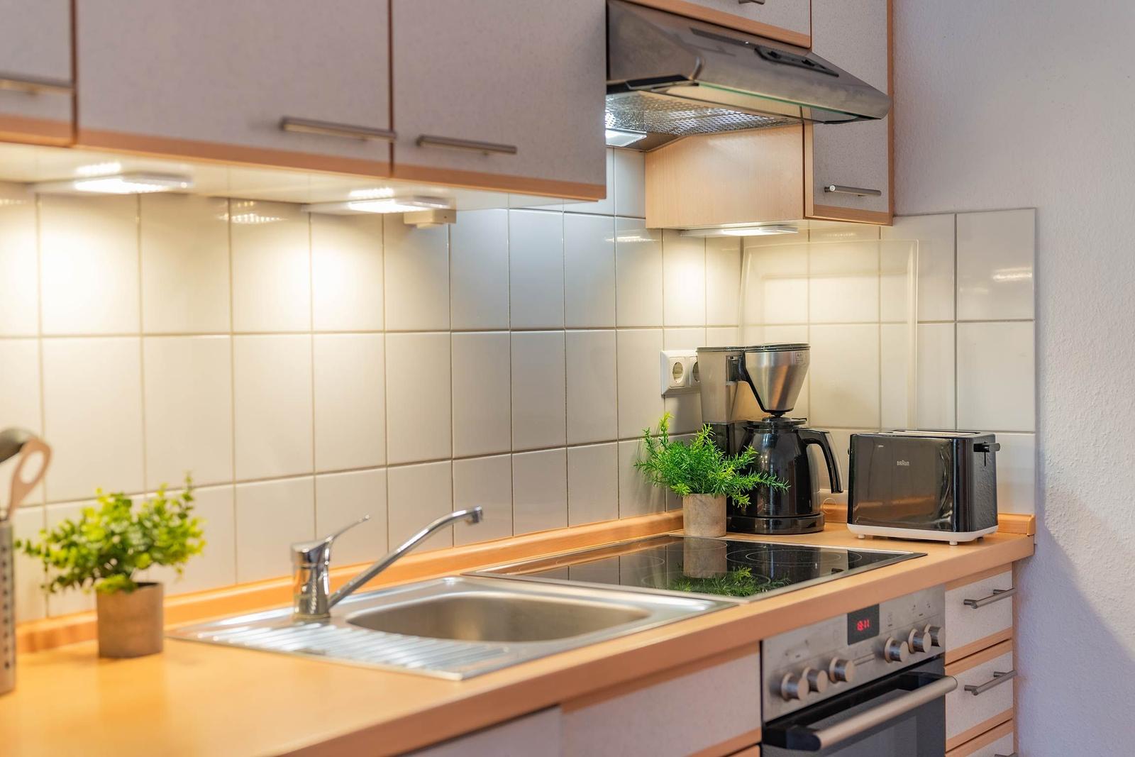 Küche mit Spüle, Herd, Kaffeemaschine und Toaster.