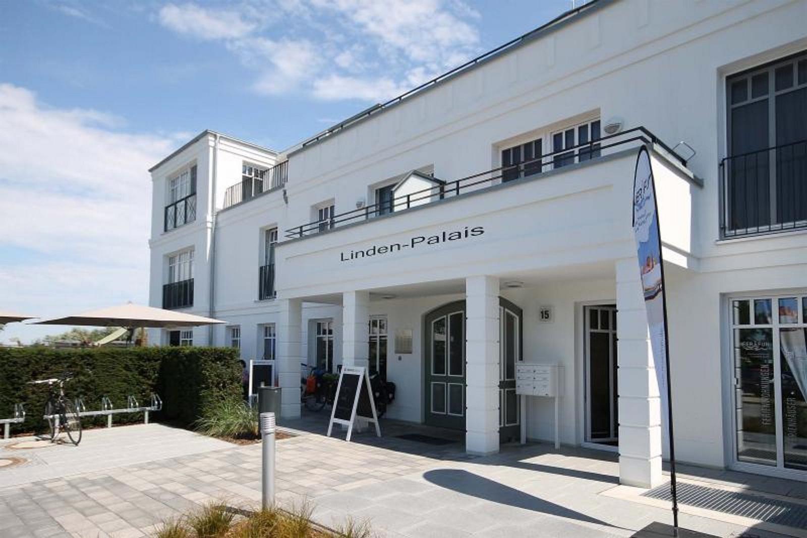 Das Linden-Palais mit Eingang, Balkonen und gepflastertem Vorplatz.