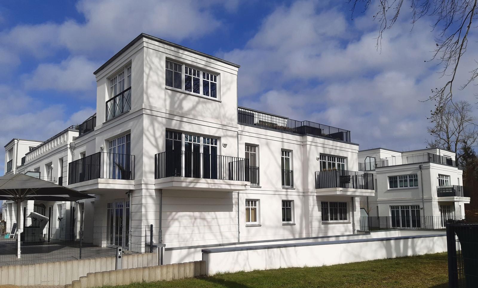 Modernes weißes Haus mit Balkonen und großzügigen Fenstern.